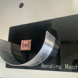 Mosqito - Metalowa taśma o szczotkowanej powierzchni precyzyjnie gięta na maszynie, z widocznym napisem 'Bending Machine' i etykietą '6X15'.