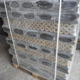 Stos pakowanych kostek opału z otworem w środku, zabezpieczony folią stretch i spięty taśmą na palecie.