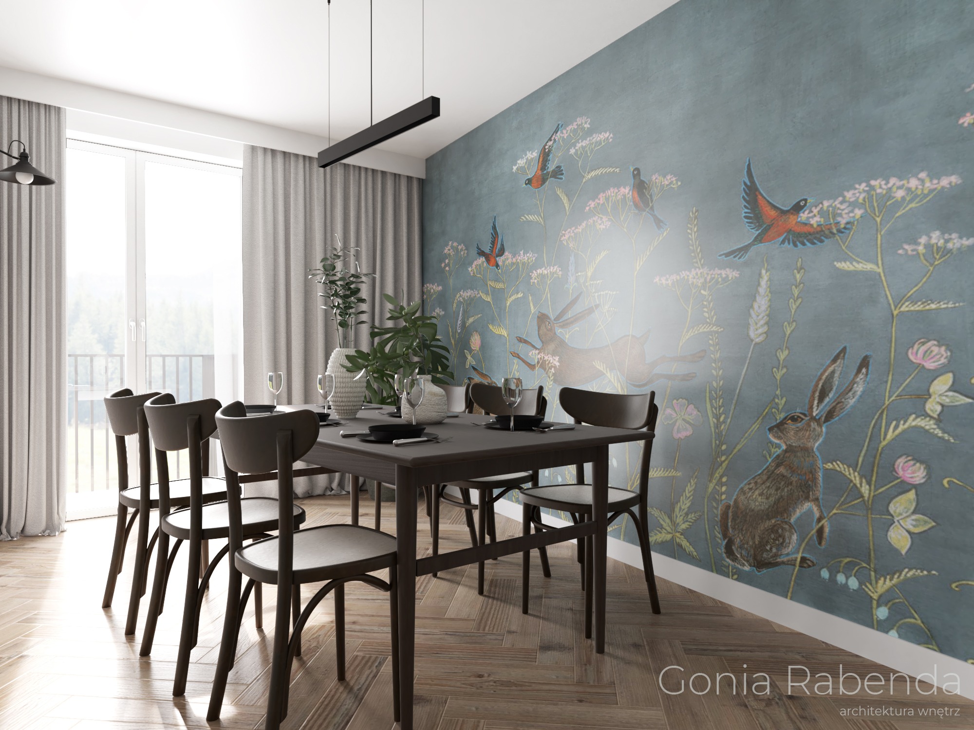 Jadalnia z drewnianym stołem i krzesłami na parkiecie w jodełkę, ściana ozdobiona malowidłami z motywem zająca i ptaków, w tle okno z widokiem na zieleń.