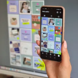 Ekran smartfona w dłoni prezentuje siatkę postów z Instagrama marki kioki.studio, z różnorodnymi grafikami i hasłami, takimi jak 'Hot news', 'Work together?' i 'Tego nie mów grafikowi', na tle...