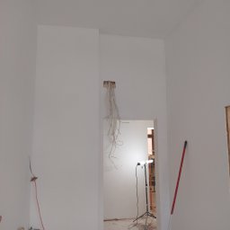 BEC-BUD FIRMA USŁUGOWO-HANDLOWA KAROL ZAGDAN - Wnętrze po malowaniu w Szczecinku: białe ściany, widoczne instalacje elektryczne i wodne, przygotowane do dalszych prac wykończeniowych. Minimalistyczny efekt.
