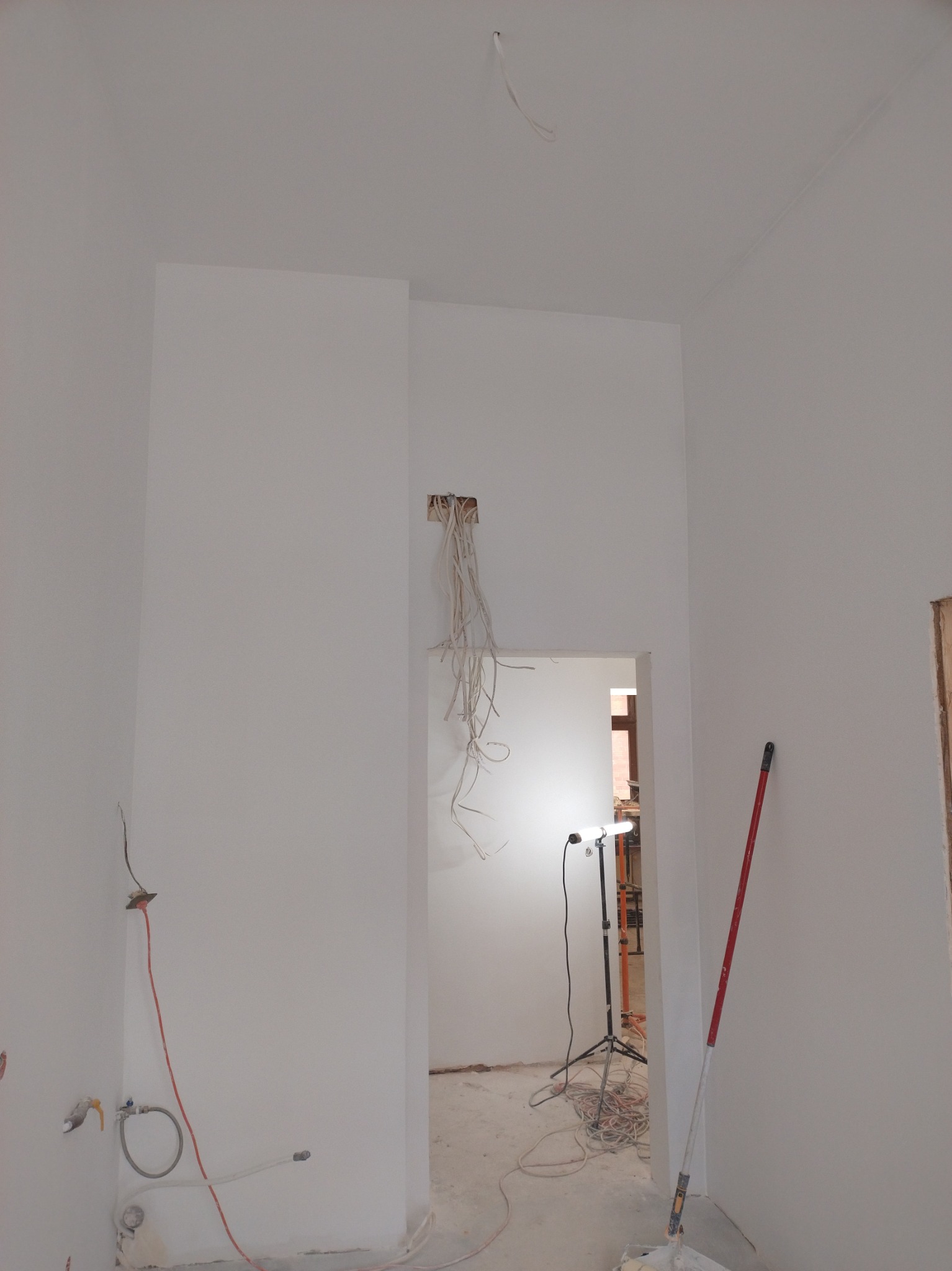 Wnętrze po malowaniu w Szczecinku: białe ściany, widoczne instalacje elektryczne i wodne, przygotowane do dalszych prac wykończeniowych. Minimalistyczny efekt.