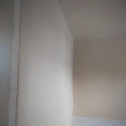 Wnętrze po tynkowaniu maszynowym, widoczne świeże tynki na ścianach i suficie, z elementami instalacji wystającymi ze ściany, przygotowane do dalszych prac wykończeniowych.