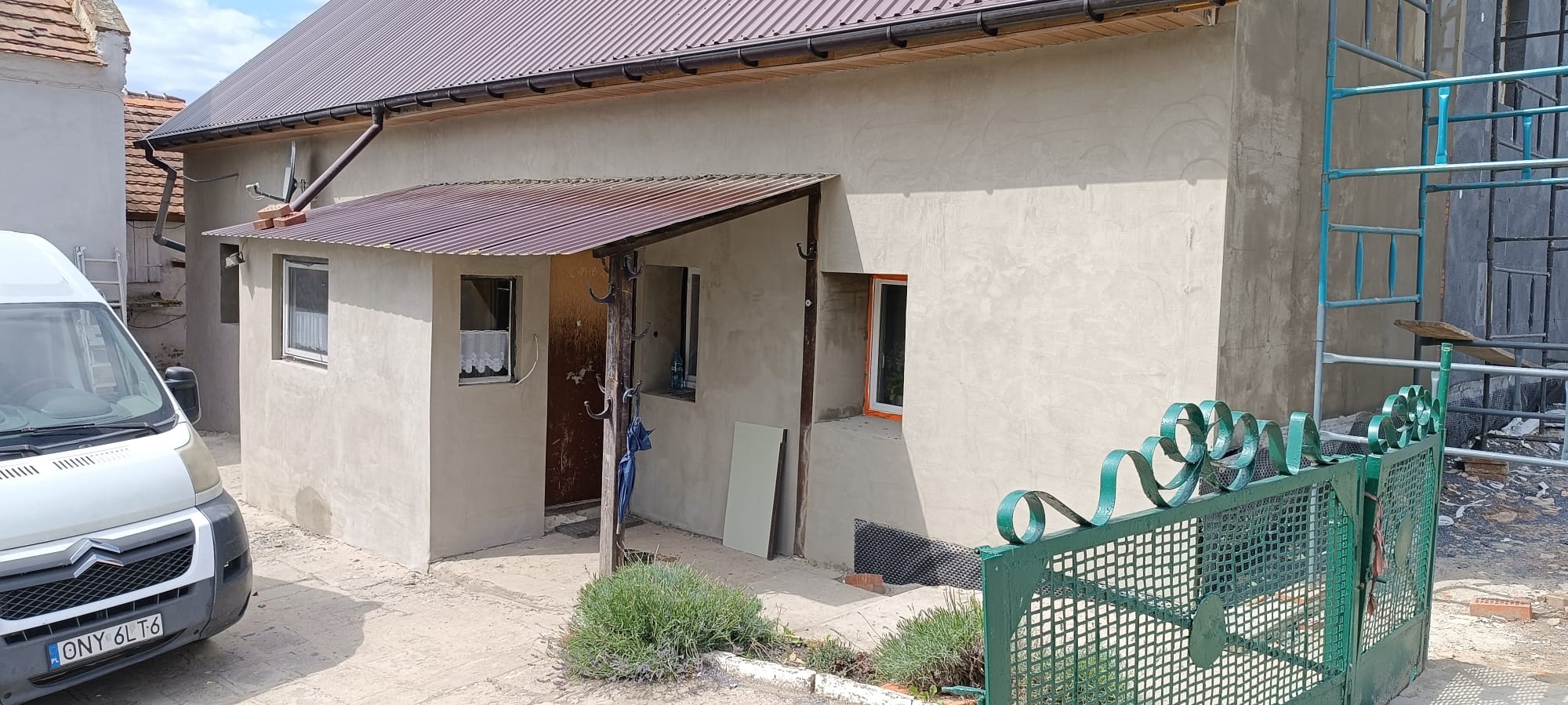 Budynek po renowacji elewacji z widocznymi rusztowaniami, nowymi rynnami i elementami wykończeniowymi.