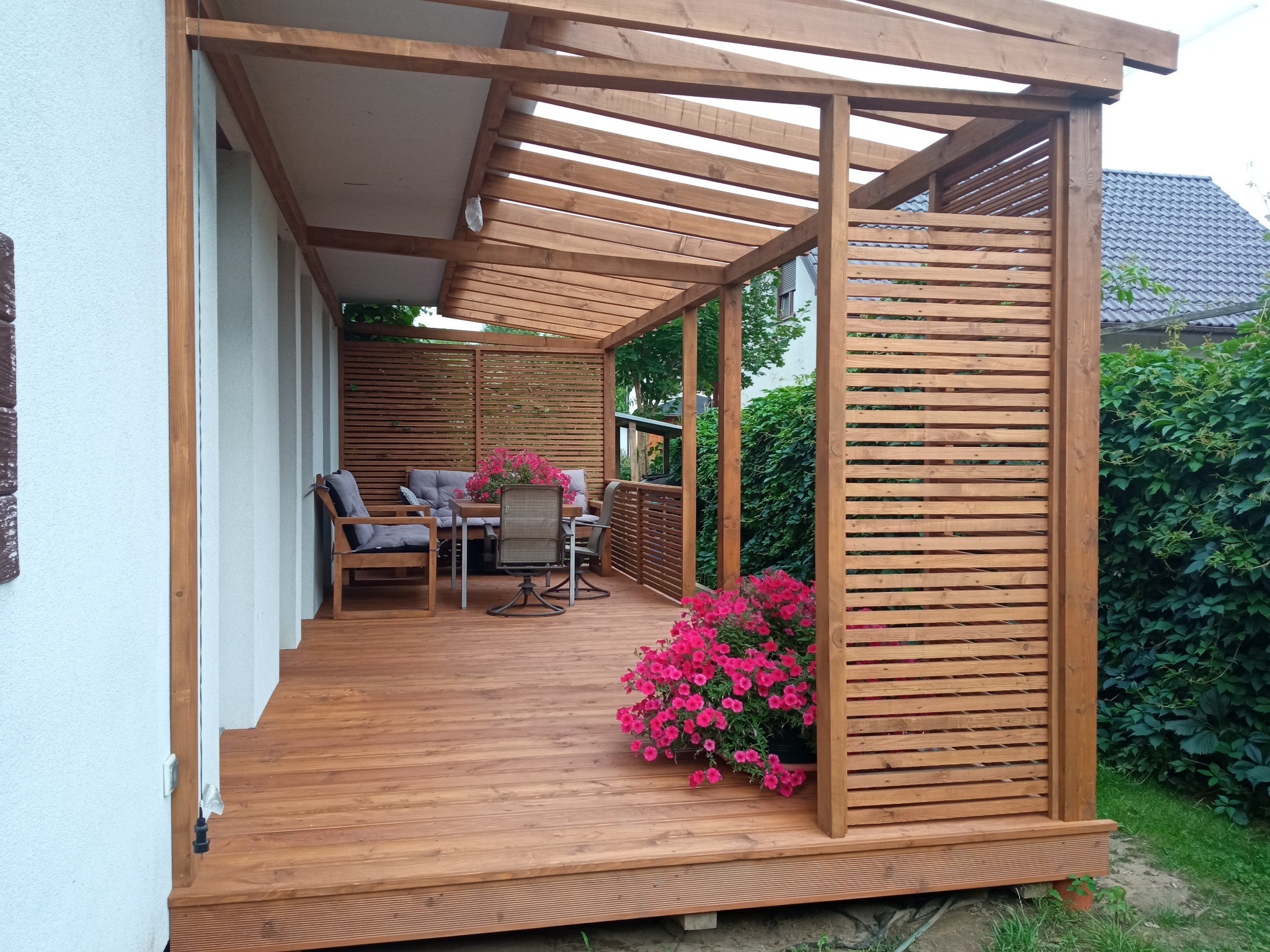 Drewniany taras z zadaszeniem z poliwęglanu.