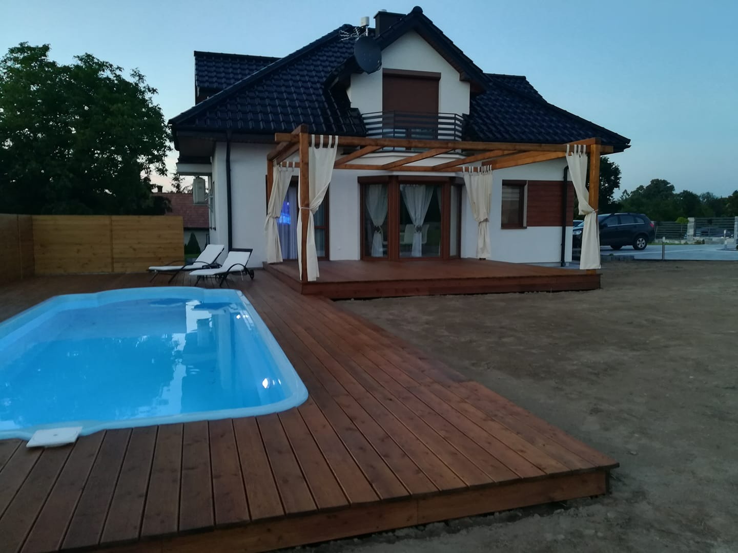 Taras z pergolą i podest z wokół basenu.