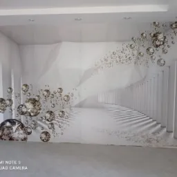 Fototapeta z motywem abstrakcyjnym, przedstawiająca iluzję tunelu z kolumnami i unoszącymi się kulami, umieszczona na ścianie w jasnym pomieszczeniu.