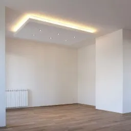 Puste, jasne wnętrze z drewnianą podłogą, białymi ścianami i sufitem podwieszanym z oświetleniem punktowym i listwą LED, widoczny grzejnik pod oknem.