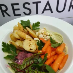 Elegancko podana sałatka z pieczonego pasternaku, baby marchewki, marynowanych grzybów i buraczków liściowych na białym talerzu, z widocznym napisem 'RESTAURANT' w tle.