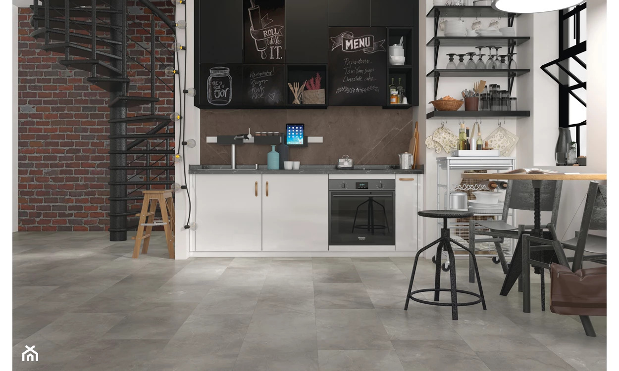 Nowoczesna kuchnia z szarą podłogą imitującą kamień, białe szafki z drewnianymi uchwytami, czarne półki i spiralne schody z ceglaną ścianą w tle.
