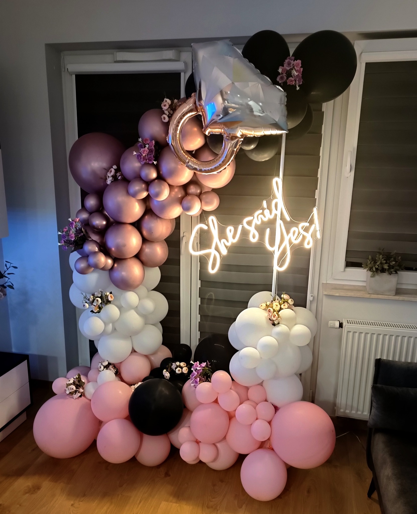 Dekoracja balonowa w odcieniach różu, bieli i czerni z motywem zaręczynowym: balon w kształcie pierścionka i neon 'She said yes!'