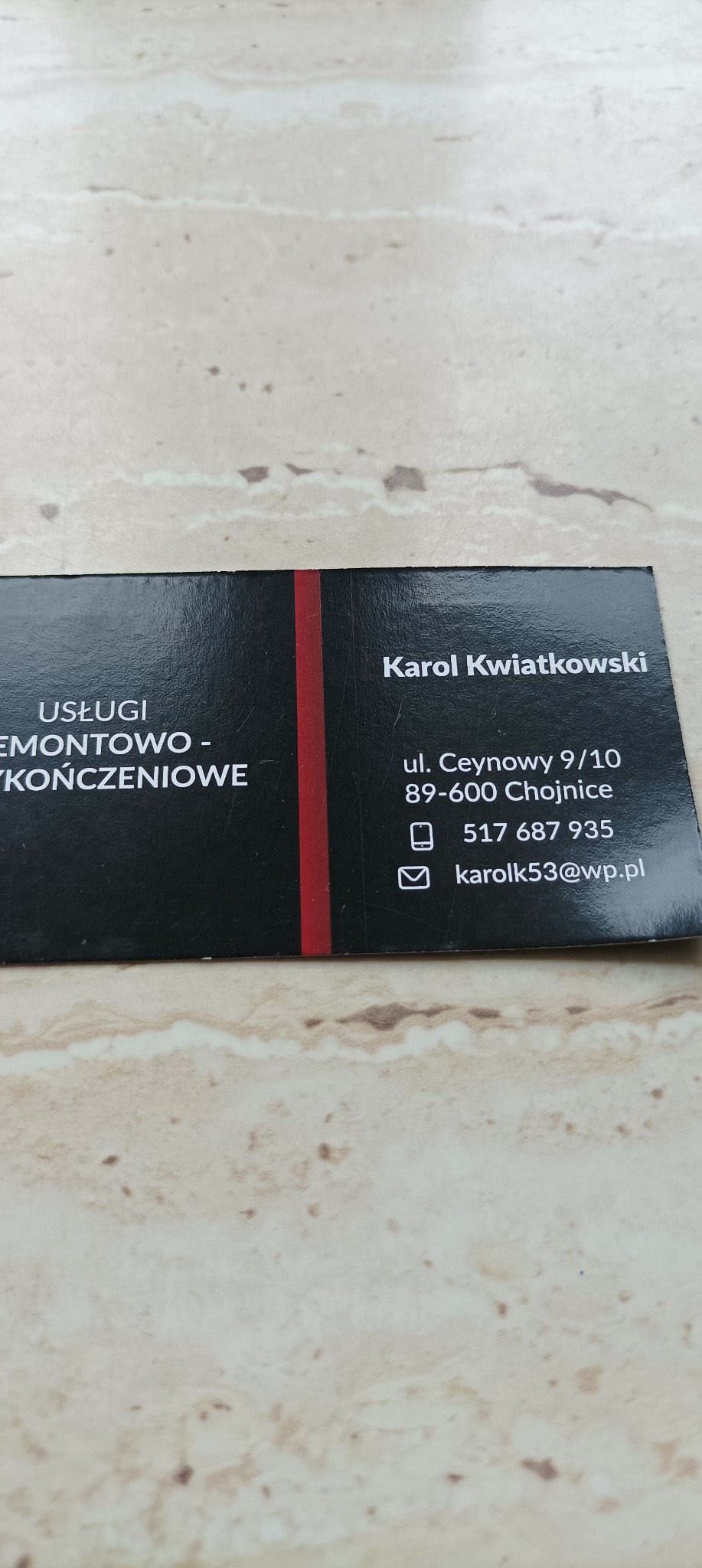 Wizytówka firmy remontowo-wykończeniowej Karol Kwiatkowski z Chojnic, z numerem telefonu i adresem e-mail, leżąca na beżowym blacie.