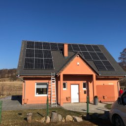 BlackSol - Pomarańczowy dom jednorodzinny z panelami słonecznymi na dachu, drabina oparta o ścianę, zaparkowany samochód dostawczy w pobliżu.