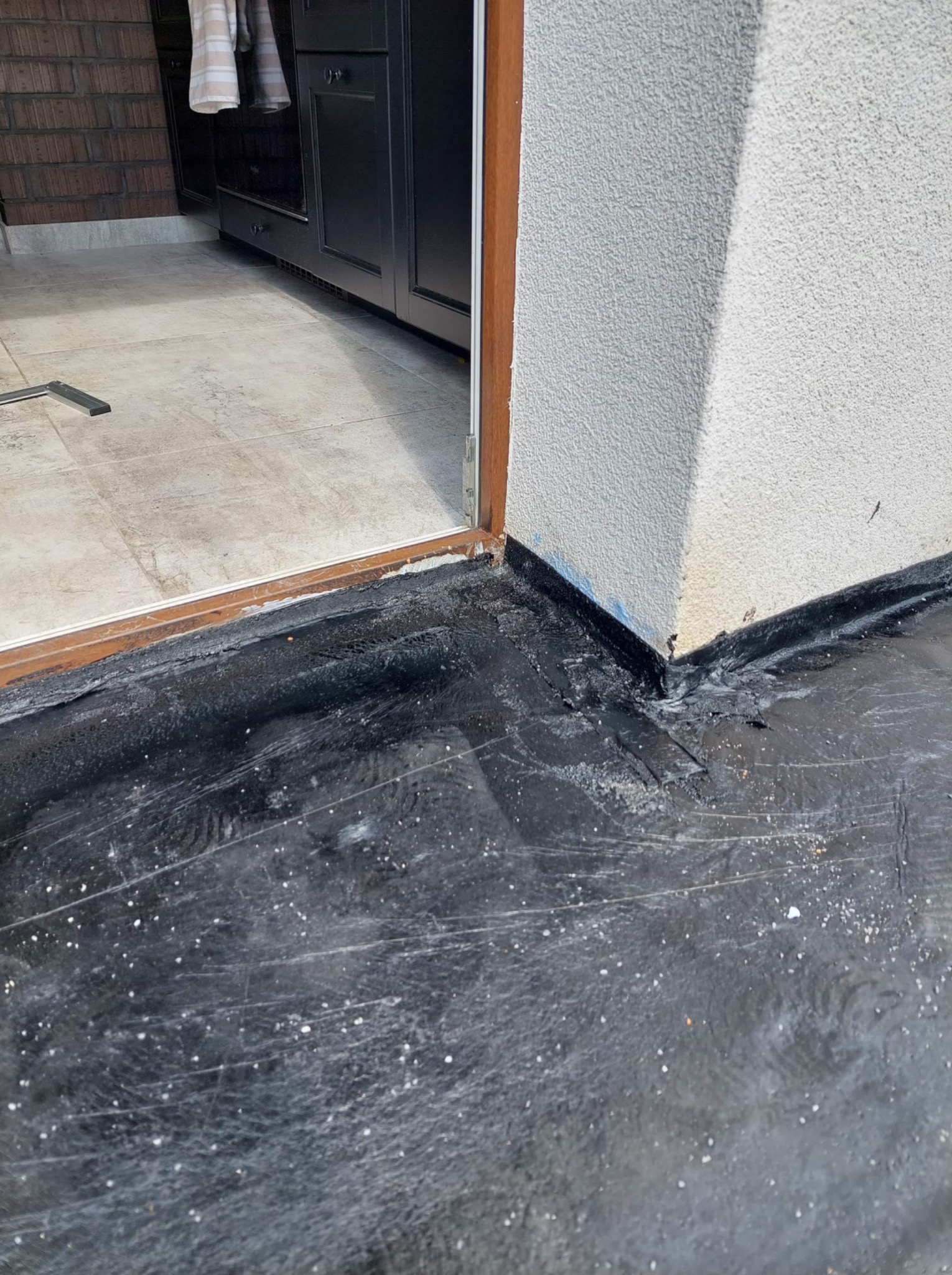 Połączenie izolacji poziomej z pionową przy drzwiach tarasowych, widoczne detale uszczelnienia i łączenia warstw izolacyjnych.