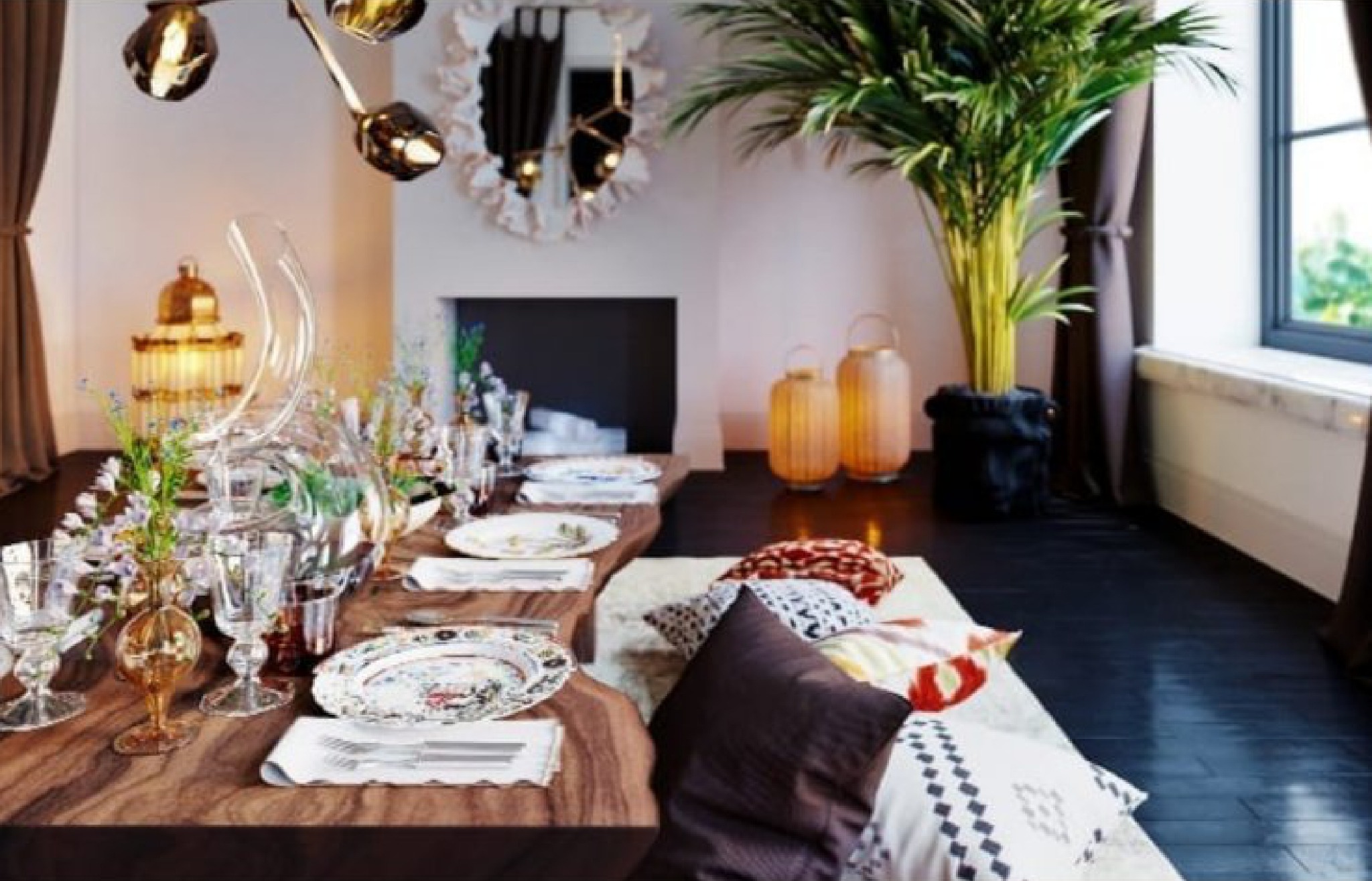 Rustykalny stół z litego drewna z zastawą, kwiatami i szklaną karafką, poduszki na podłodze, lustro w ozdobnej ramie i palma w salonie.