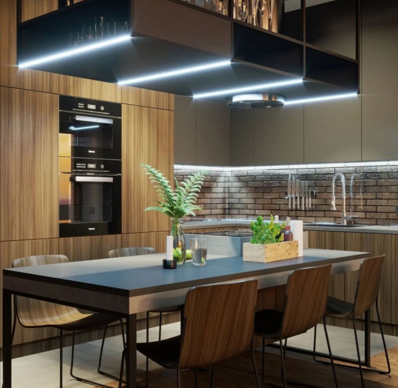 Nowoczesna kuchnia z drewnianymi frontami, oświetleniem LED pod szafkami, ceglaną ścianą nad blatem, stołem z ciemnym blatem i drewnianymi krzesłami oraz dekoracjami roślinnymi.
