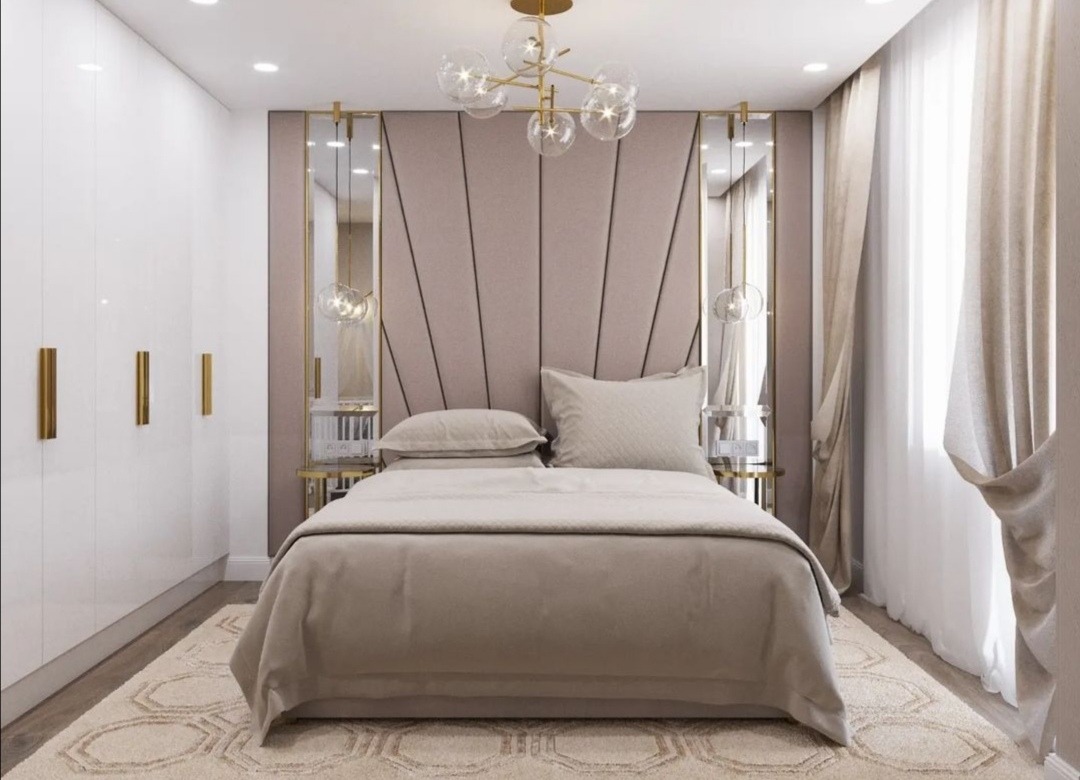 Elegancka sypialnia w odcieniach beżu z tapicerowanym zagłówkiem, lustrami po bokach, nowoczesną lampą sufitową i białymi szafami.