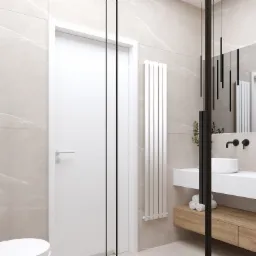 Minimalistyczna łazienka z beżowymi płytkami imitującymi marmur, białą umywalką nablatową, czarną armaturą, wiszącymi lampami tubami oraz białym grzejnikiem drabinkowym i drzwiami.