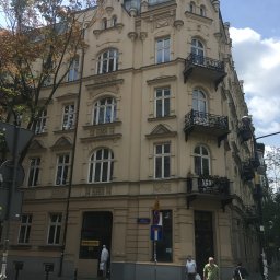 Polbyte Artur Olszak - Kamienica w stylu eklektycznym z kopułą, balkonami i ozdobnymi detalami architektonicznymi, widoczna z poziomu ulicy z przechodniami.