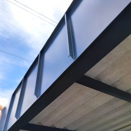 Dach-bud Dariusz matecki - Nowoczesna, grafitowa obróbka blacharska dachu z widocznym podsufitką oraz fragmentem nieba z przewodami elektrycznymi w tle.