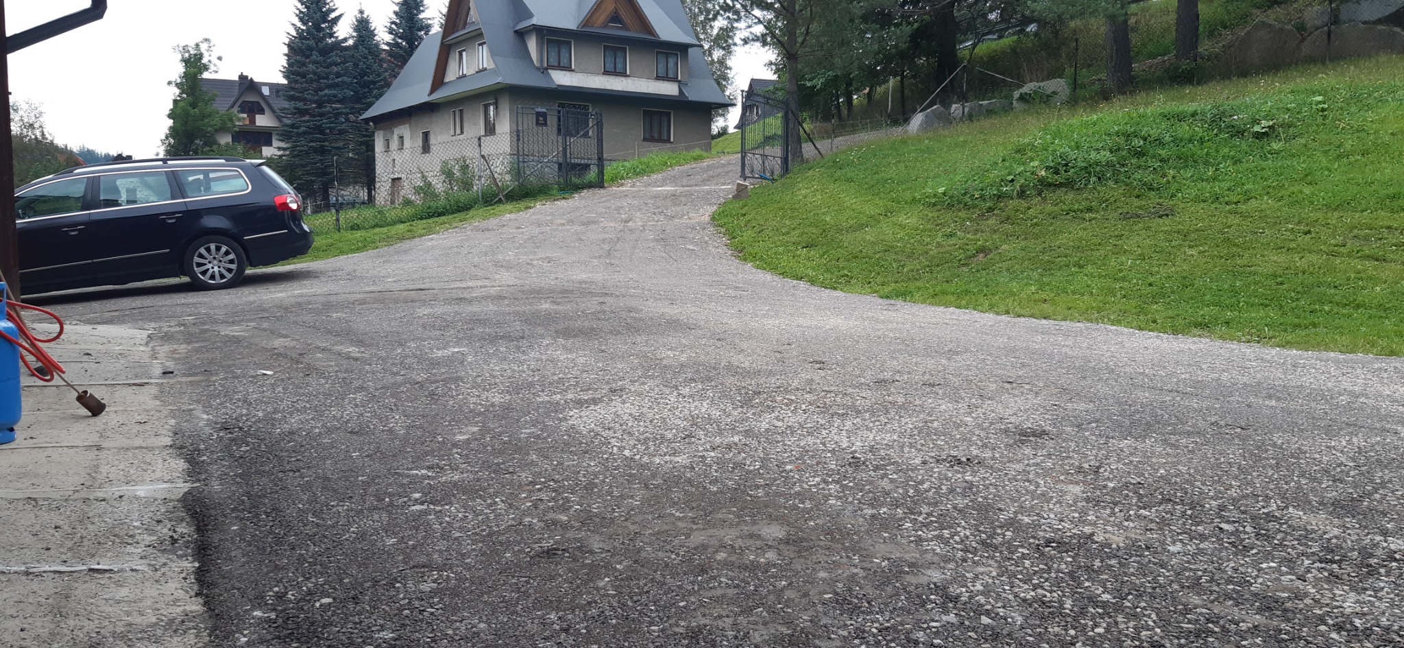 Nowo położona nawierzchnia żwirowa na podjeździe do domu, widoczny sprzęt do układania nawierzchni i samochód osobowy.