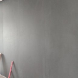 VASYL TSIUPA - Świeżo położona, ciemnoszara ściana z widocznym poziomem w rogu, sugerująca prace wykończeniowe w trakcie.