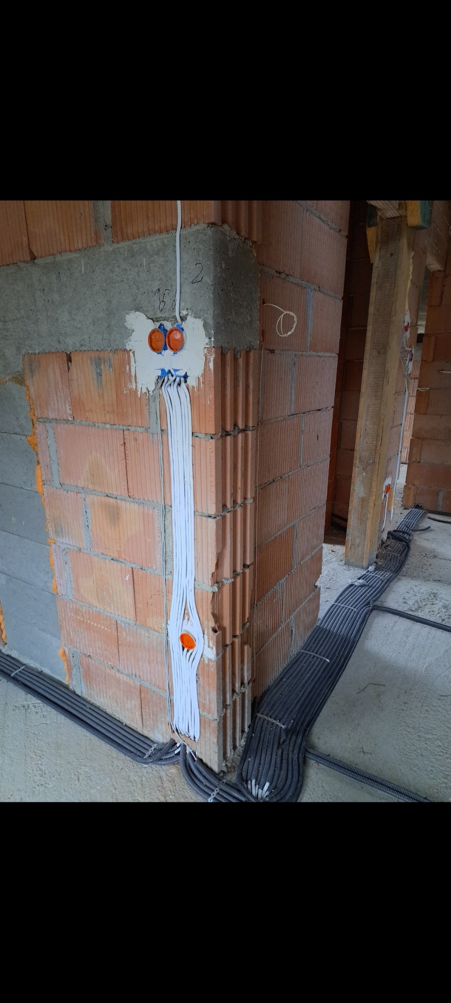 Instalacje elektryczne w surowym budynku w Pawlikowicach. Widoczne kable prowadzone w ścianach i po podłodze, przygotowane do dalszych prac wykończeniowych.