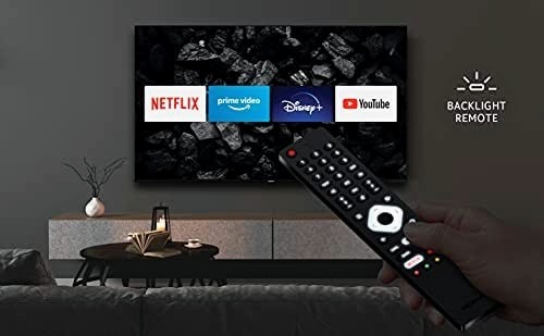 Telewizor z widocznymi ikonami Netflix, Prime Video, Disney+ i YouTube, obsługiwany pilotem z podświetleniem, ustawiony w nowoczesnym salonie z minimalistycznym wystrojem.
