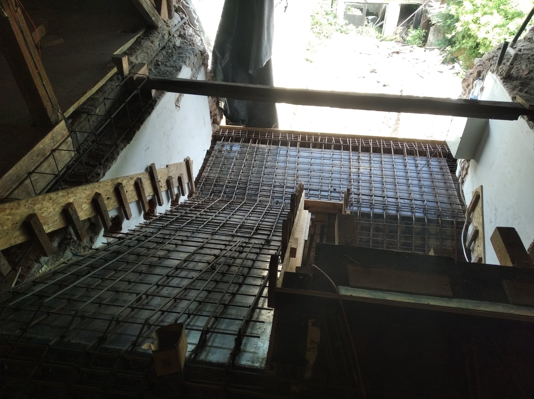 Zbrojenie pod wylewkę stropu w trakcie prac remontowych w budynku z odsłoniętą konstrukcją, widoczne drewniane szalunki i siatka zbrojeniowa.