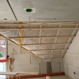 Konstrukcja drewniana pod ocieplenie poddasza z folią paroizolacyjną, widoczne płyty karton gips na ścianach i surowy betonowy strop z otworem na instalację