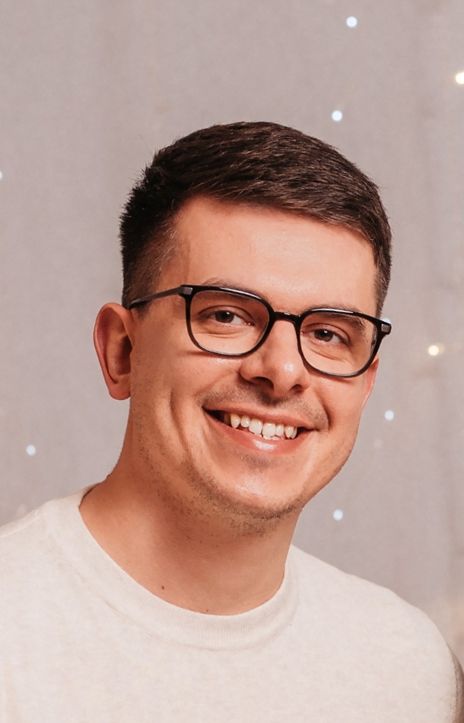 Portret uśmiechniętego mężczyzny w okularach na tle światełek bokeh.