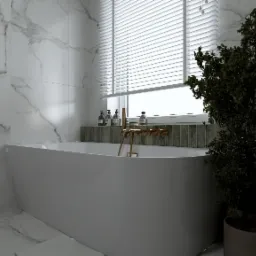 Nowoczesna łazienka z białą wanną wolnostojącą, złotą armaturą i marmurowymi płytkami, doświetlona przez żaluzje okienne, z rośliną doniczkową jako element dekoracyjny.