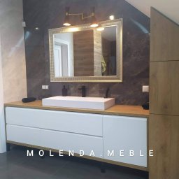 Molenda Meble Na Wymiar - Nowoczesna łazienka z białą szafką pod umywalkę z drewnianym blatem, lustrem w złotej ramie i marmurowymi płytkami na ścianie.