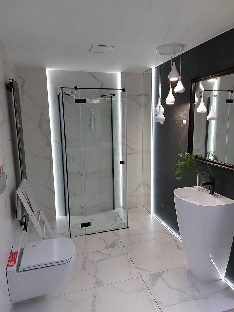 Nowoczesna łazienka z kabiną prysznicową typu walk-in z czarnymi profilami, wiszącą toaletą z podestem, umywalką wolnostojącą i marmurowymi płytkami.