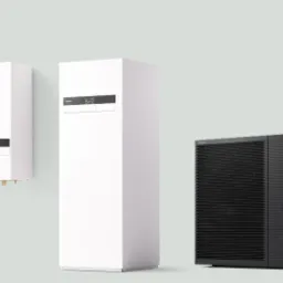 Dwie białe jednostki wewnętrzne i czarna jednostka zewnętrzna pompy ciepła Panasonic Aquarea, na jasnym tle.