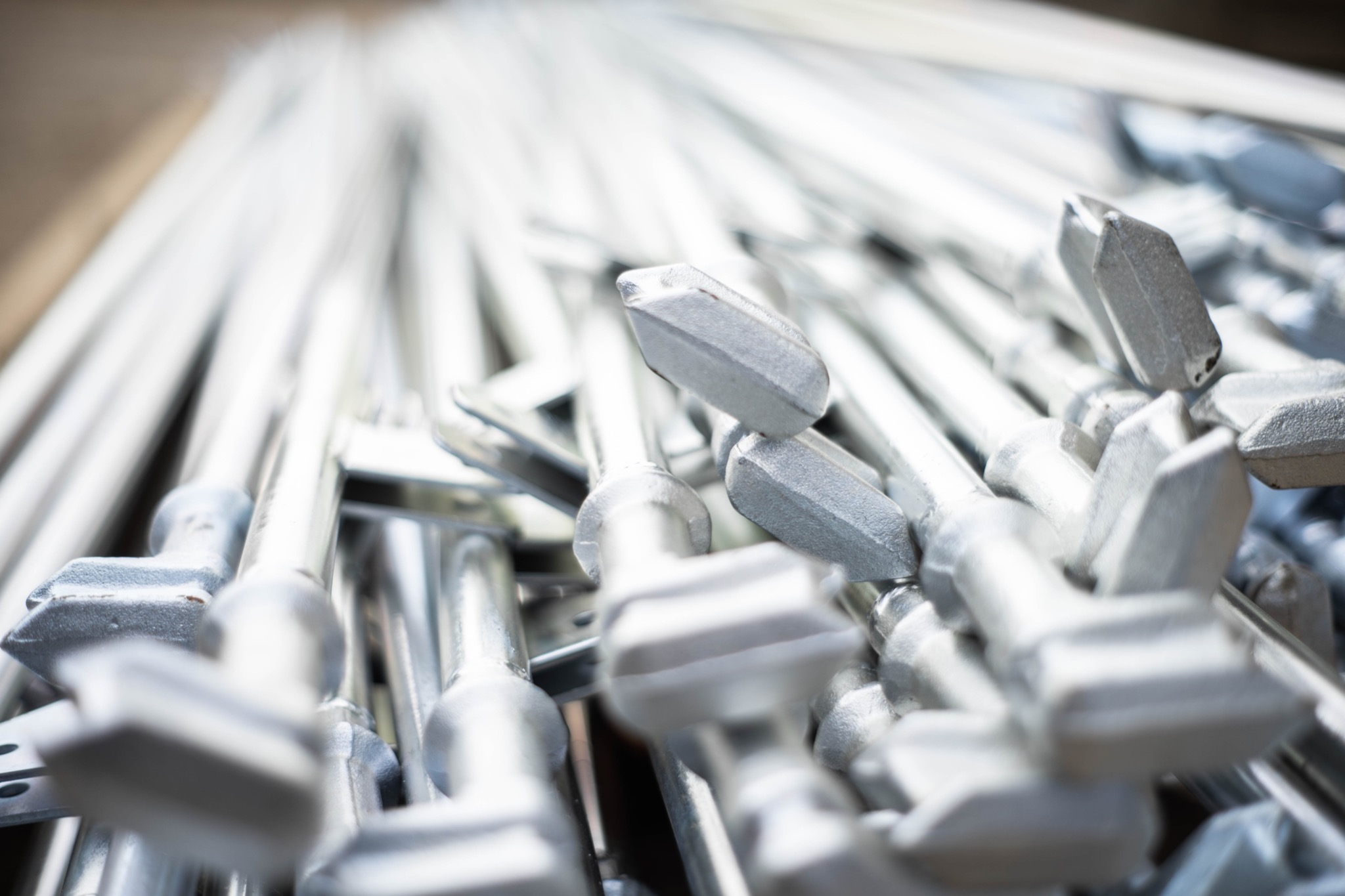 Stalowe podpory rusztowań budowlanych, widoczne z bliska, ułożone warstwami pod kątem, z wyraźnym pierwszym planem i rozmytym tłem.