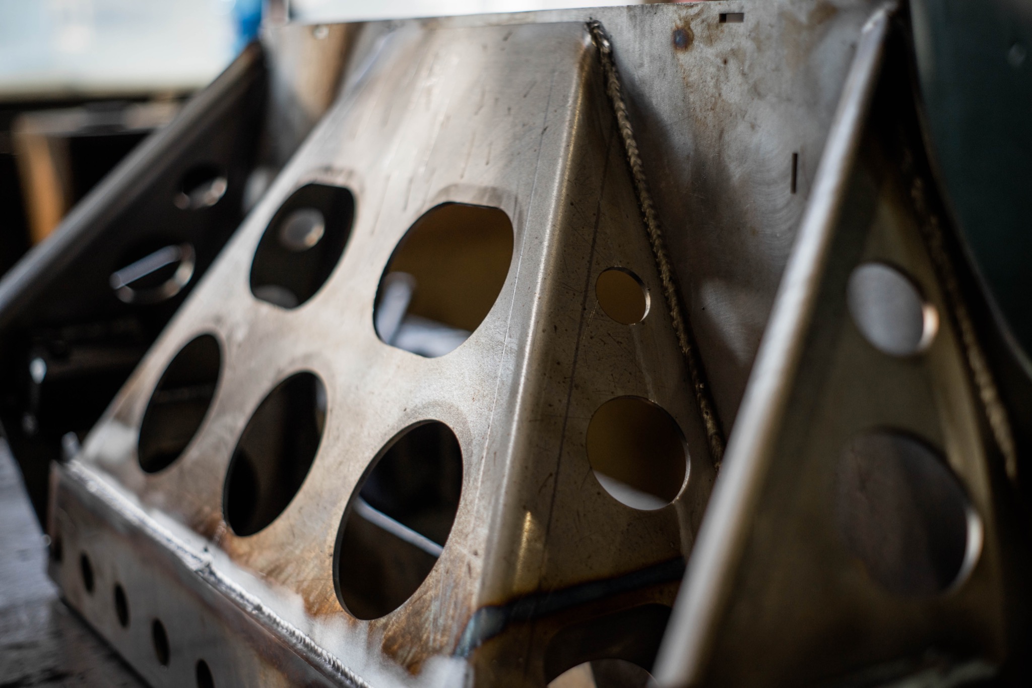 Konstrukcja metalowa z otworami, spawana z widocznymi śladami obróbki, ustawiona na stole warsztatowym.