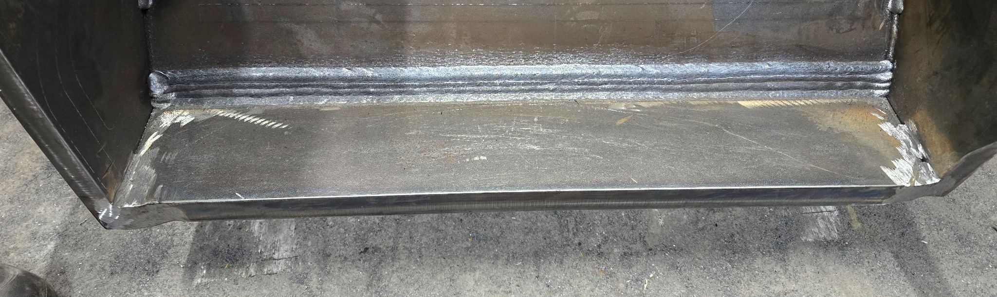 Metalowa konstrukcja po spawaniu, widoczne spoiny. Surowy metal, szlifowane krawędzie. Detal konstrukcji stalowej, zbliżenie na miejsce łączenia elementów.