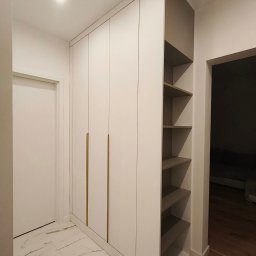BlackForest Adrian Bonowski - Biała szafa wnękowa z złotymi uchwytami i otwartymi półkami w przedpokoju z marmurową podłogą. Minimalistyczny design, oświetlenie sufitowe.