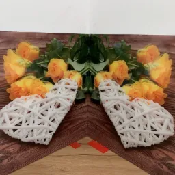 Szklana ściana dekoracyjna z motywem żółtych róż i białych serc z wikliny, imitacja drewnianej powierzchni, widoczne czerwone elementy montażowe.