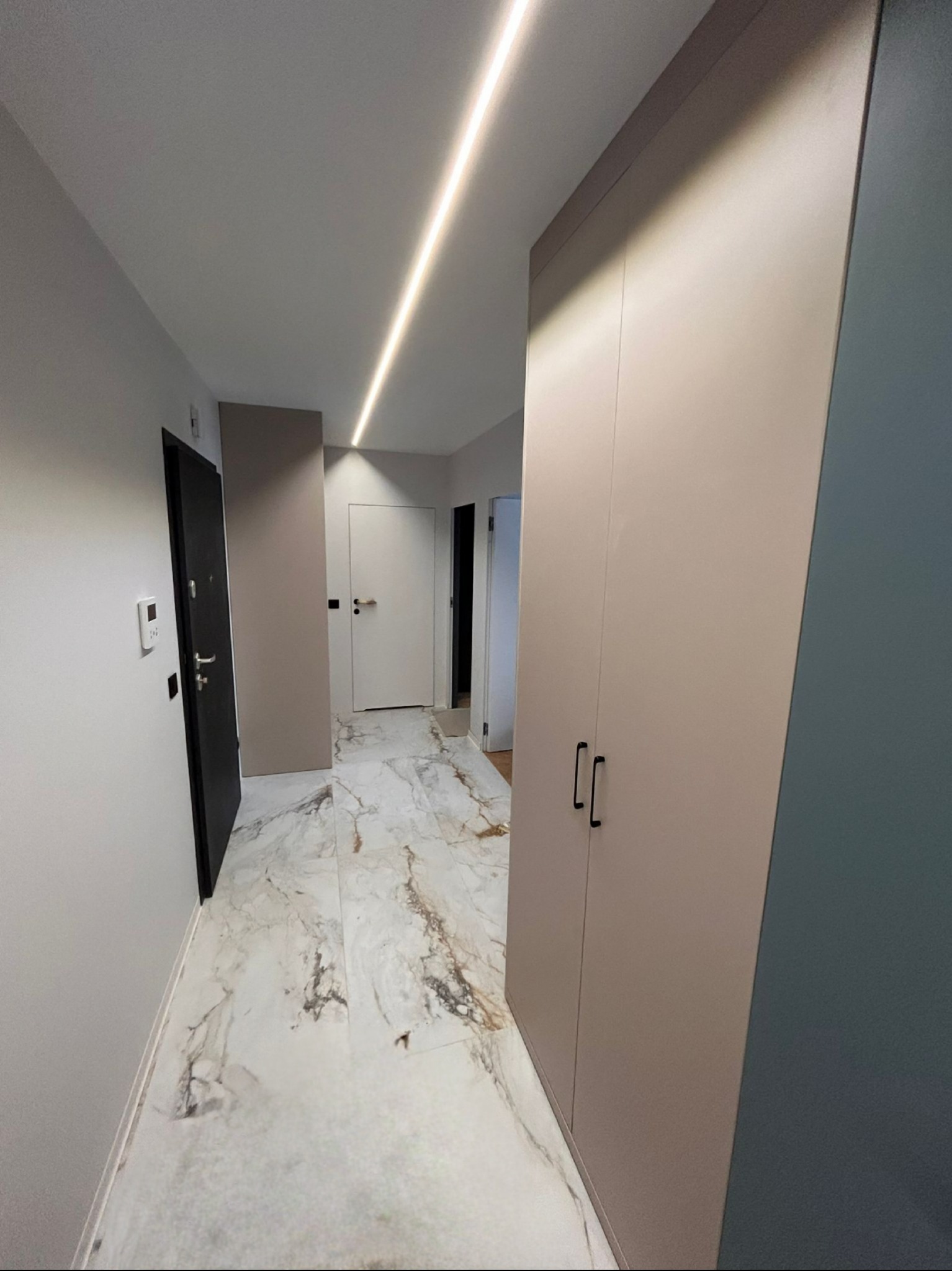 Nowoczesny przedpokój we Wrocławiu z marmurową podłogą, szafą w zabudowie i oświetleniem LED. Minimalistyczny design, jasne kolory, eleganckie wykończenie.