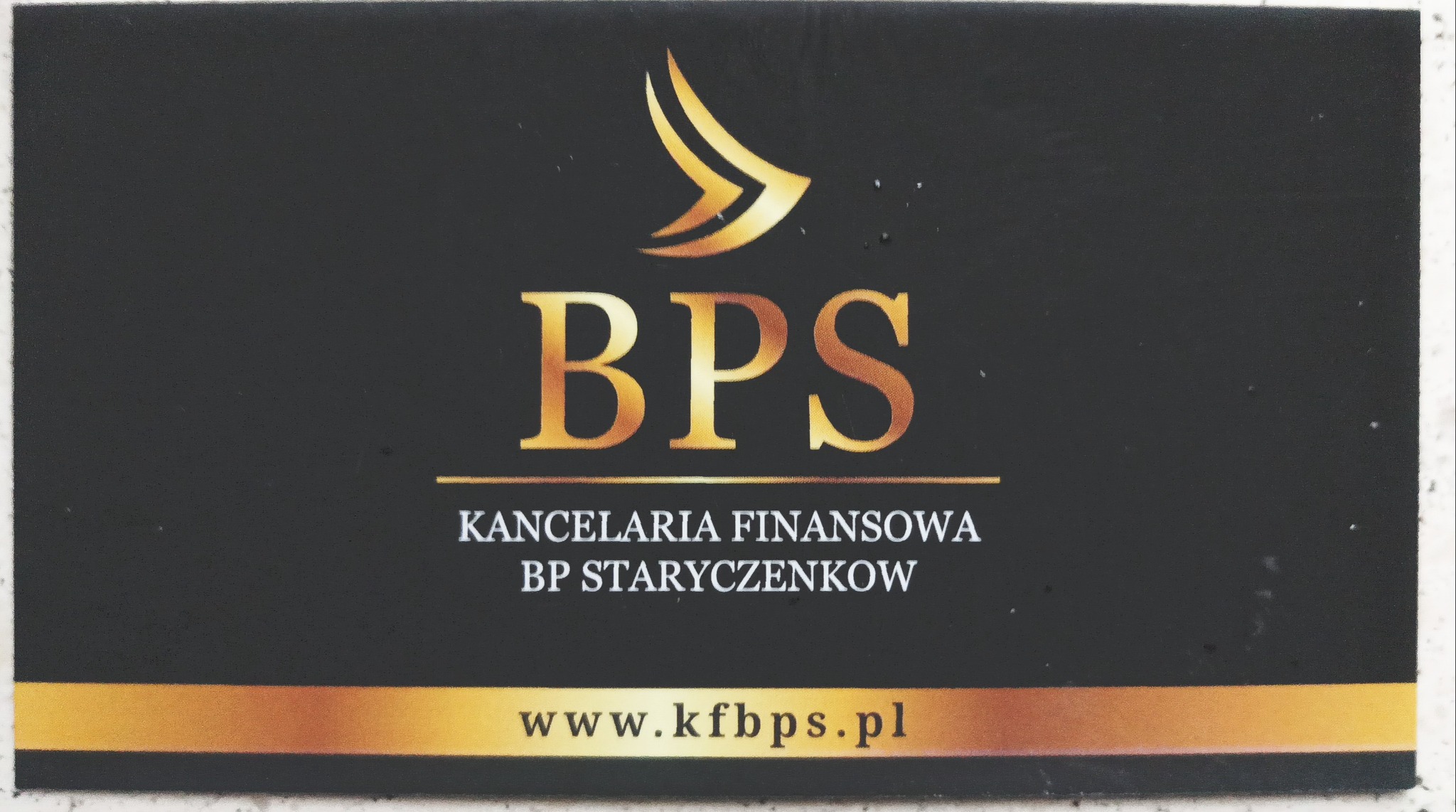 Wizytówka Kancelarii Finansowej BP Staryczenkow z logo BPS w kolorze złotym na czarnym tle, adres strony internetowej www.kfbps.pl