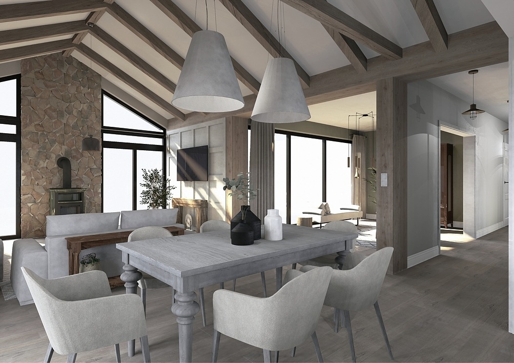 Wnętrze domu z wysokim stropem, drewnianymi belkami, kamienną ścianą i dużymi oknami, w centrum stół jadalny z szarymi krzesłami i ozdobnymi wazonami, w tle salon z sofą i kominkiem.