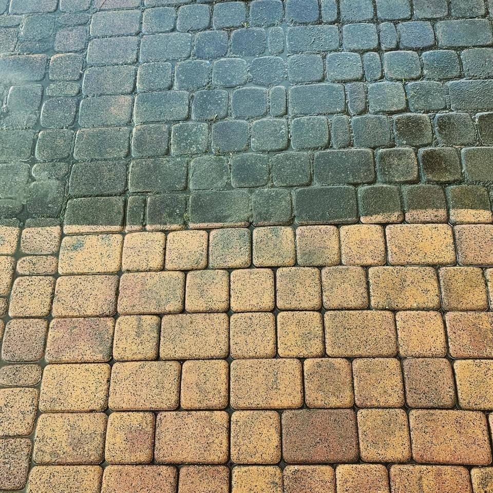 Częściowo wyczyszczona kostka brukowa, widoczny kontrast między brudną, ciemną powierzchnią a czystą, jasnobrązową częścią.