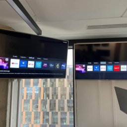 MIB Systemy Zabezpieczeń - Dwa telewizory zamontowane na ścianie w biurze, wyświetlające menu z aplikacjami streamingowymi. Jeden telewizor pokazuje brak połączenia z siecią.