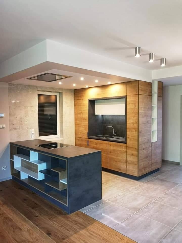 Nowoczesna kuchnia z wyspą, drewnianymi szafkami i marmurowymi płytkami na ścianie w tle okna z żaluzjami.