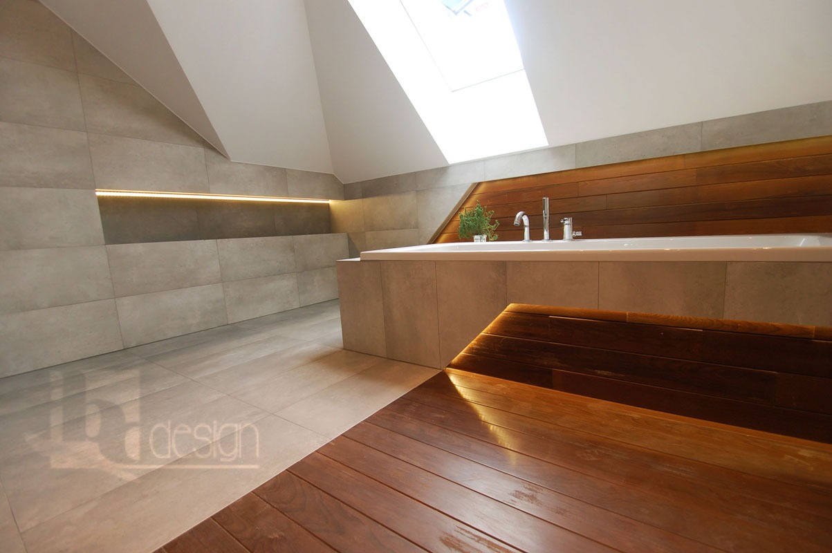 Nowoczesna łazienka na poddaszu z drewnianymi akcentami, podświetlaną wnęką i drewnianym podestem prowadzącym do wanny.