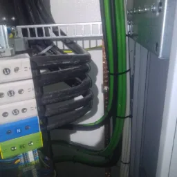 Wnętrze szafy elektrycznej z uporządkowanymi przewodami, listwami zaciskowymi oznaczonymi L1, L2, L3 i N, oraz metalową szyną uziemiającą.