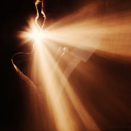 Fotograf Anna Shaulskaya - Abstrakcyjne zdjęcie z promieniami światła w odcieniach brązu i pomarańczy, padającymi przez wąską szczelinę, tworząc dramatyczny efekt wizualny.