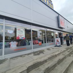SD-UNION Dariusz Stachowiak - Widok zewnętrzny sklepu KiK z odzieżą i artykułami gospodarstwa domowego, z widocznymi witrynami wystawowymi, schodami wejściowymi i szyldem z logo marki.